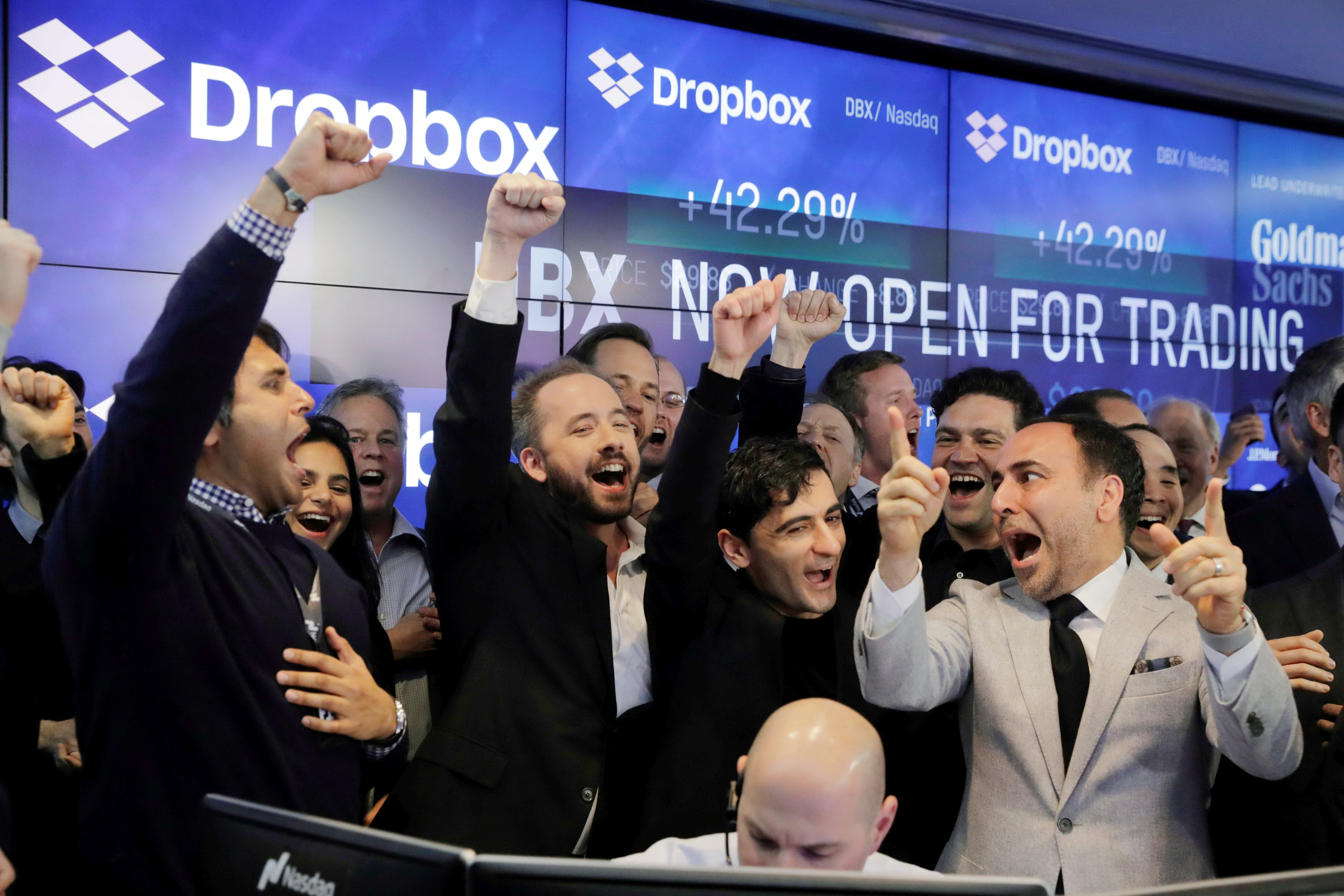 Dropbox上市首日成績優異，創辦人休斯敦（前排左二）和菲爾多西（前排左三）在納斯特交易所內雀躍歡呼。（路透圖片）