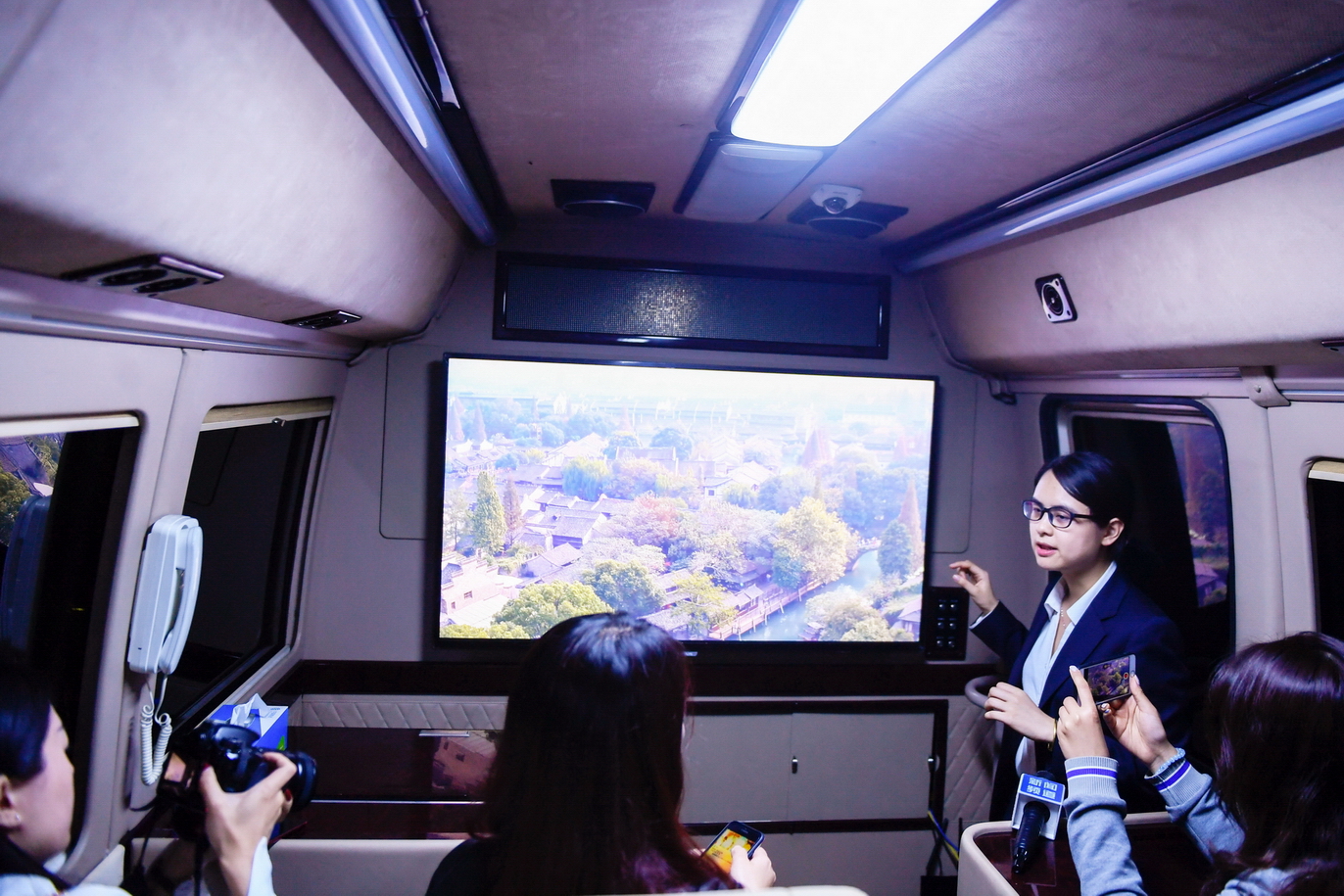 在浙江移動烏鎮分水墩營業廳外，工作人員在一輛體驗巴士內介紹通過5G移動傳輸技術實現的8K高清的視頻畫面實時展示。（新華社圖片）