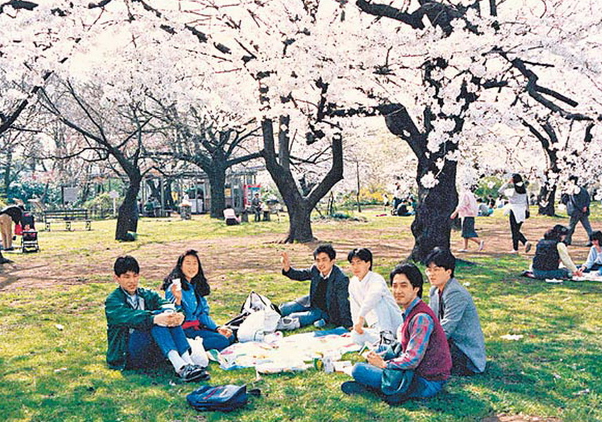 劉雲輝（右四）早年在日本生活時跟友人在櫻花樹下野餐。（受訪者圖片）