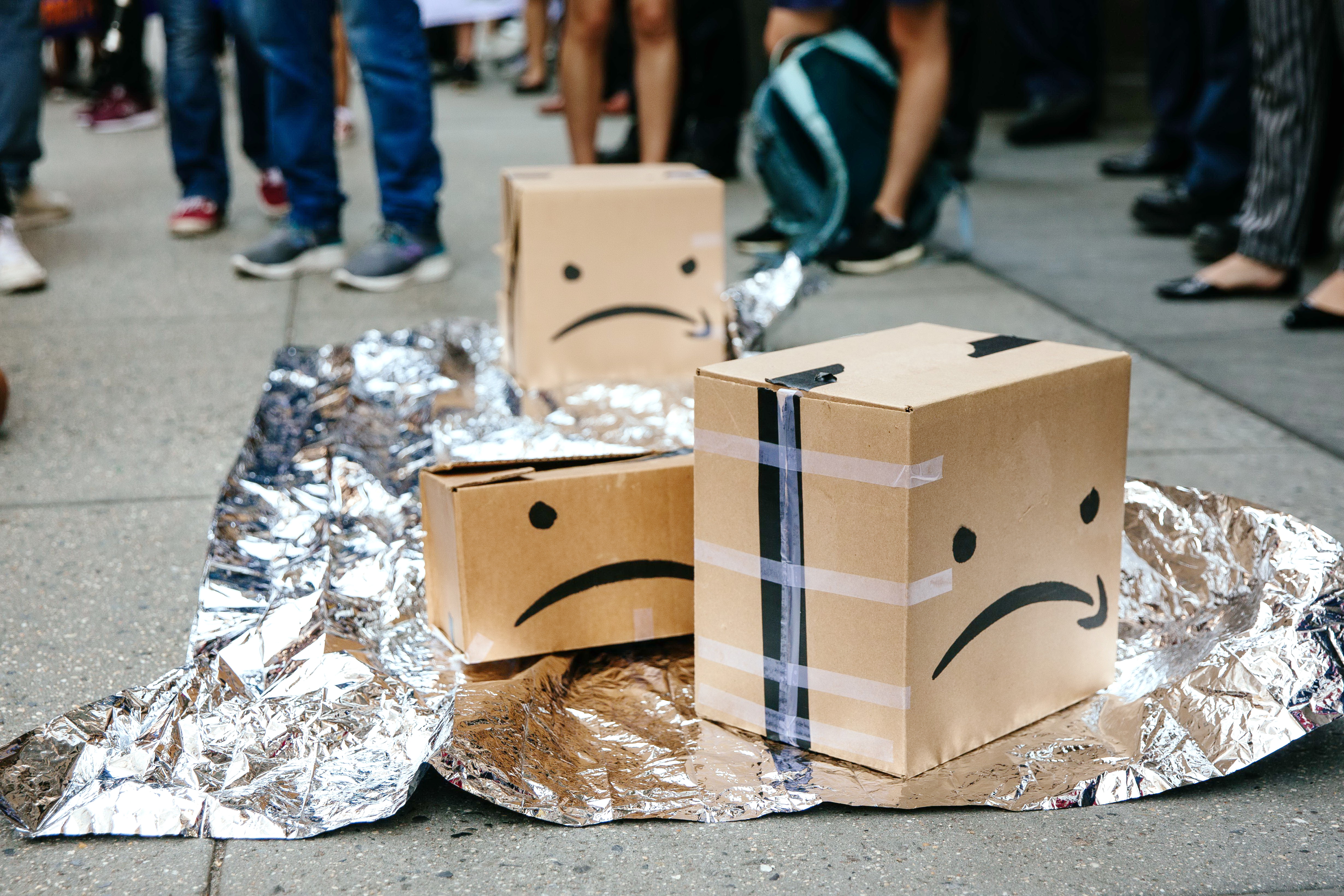 紐約示威者在紙箱畫了一張苦臉，控訴加班帶來的血汗災難。（法新社圖片）