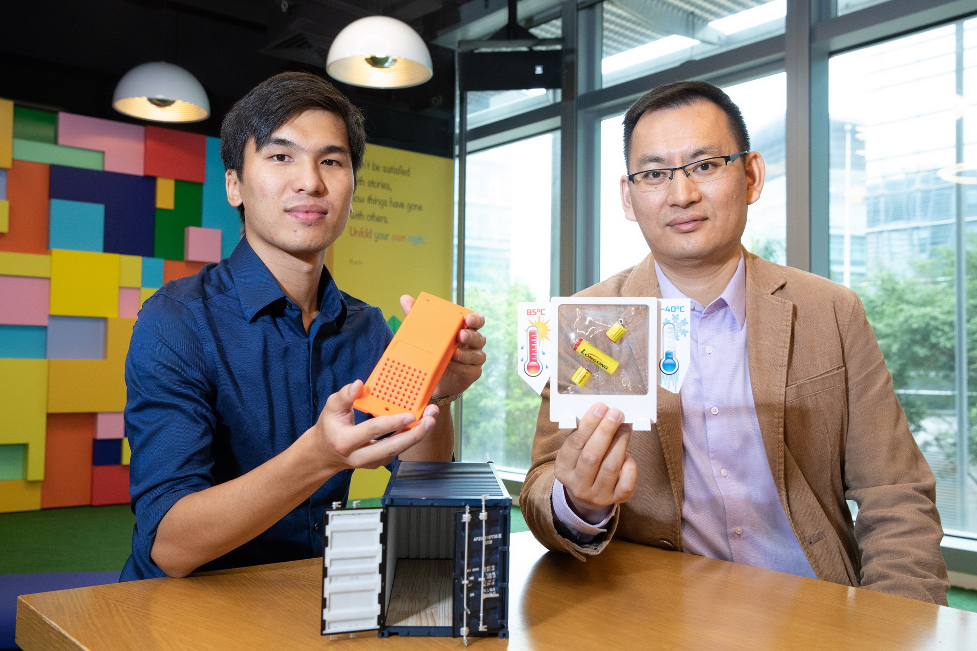 納米及先進材料研發院代表：工程師王煒賢（左）及技術經理路勝博博士（右）手持應用極端溫度電池的智能物流追蹤器。（香港科技園圖片）