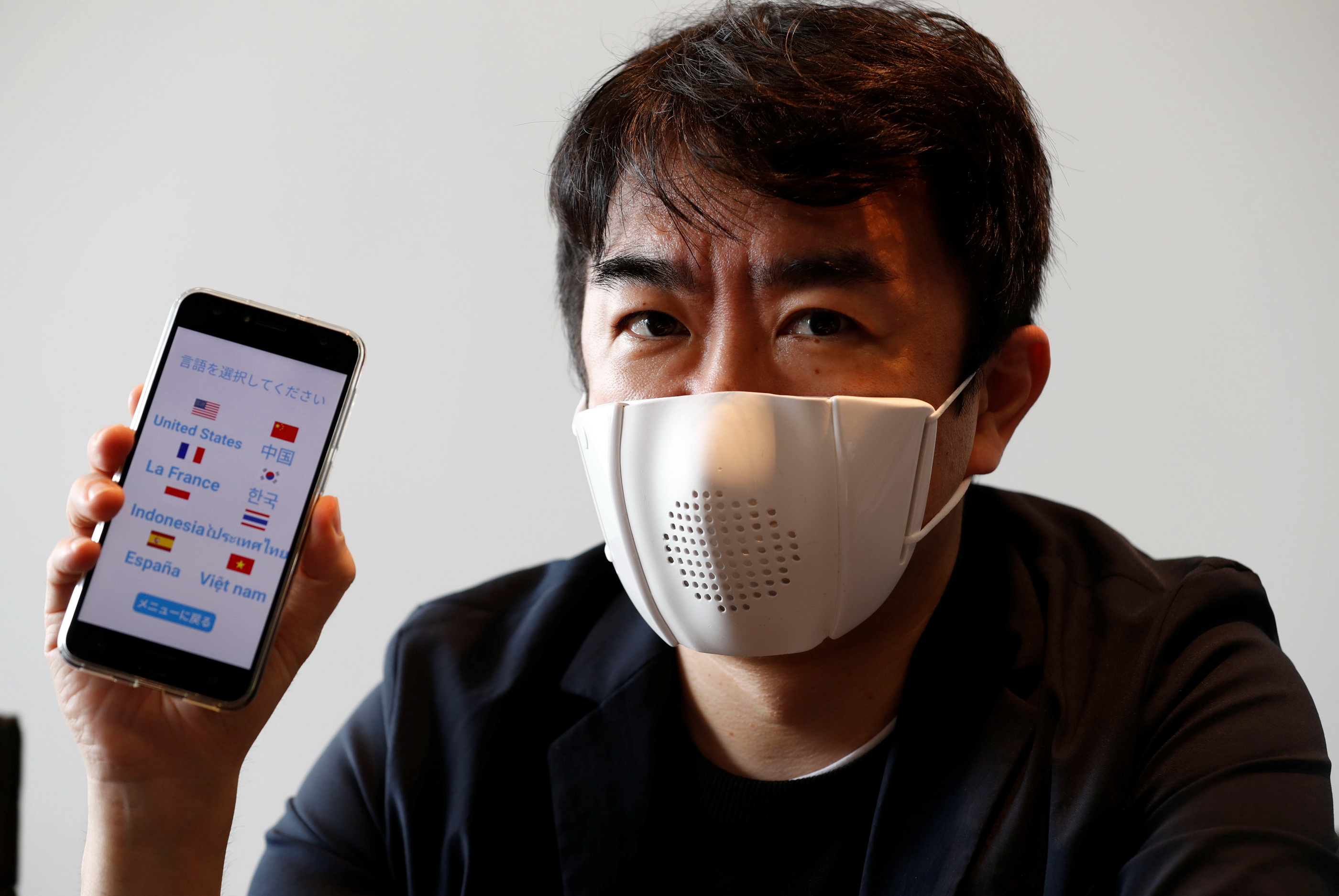 Donut Robotics小野泰助戴上c-mask，展示該口罩經由手機把日語翻譯為其他外語的功能。（路透圖片）