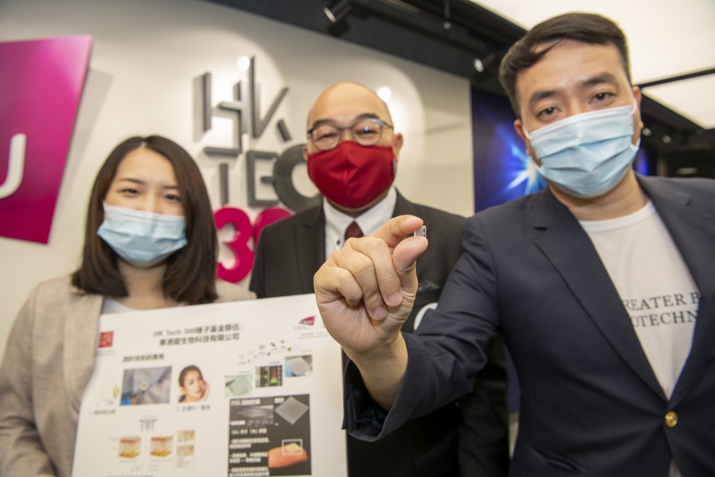 華港龍生物科技代表伍子龍（右）及團隊成員鄭梦佳博士（左）展示他們研發的微針，香港生物醫藥創新協會常務會董陳晉宇（中）為他們的創業導師。
