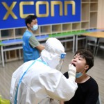 Medical worker collects a swab from a worker at a Foxconn factory, following new COVID-19 cases in Wuhan