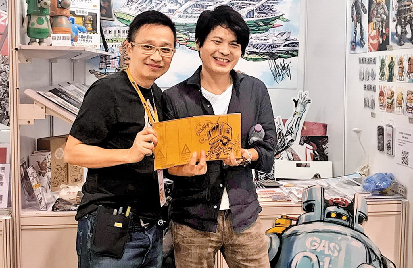 《超時空要塞》模型盒插畫畫家天神英貴（右）來港時，到Felix（左）擺設於展覽內的攤位購買《香港重機》繪本。（受訪者Facebook圖片）